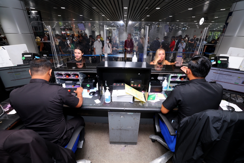 File picture of Immigration officers processing entry documents for tourists entering Malaysia. Immigration officers stationed at KLIA Terminal 1 and Terminal 2 are now prohibited from using mobile phones while on duty to prevent a recurrence of ‘counter setting’ syndicates, which allow foreign nationals to enter the country through ‘special counter lanes’. — Bernama pic