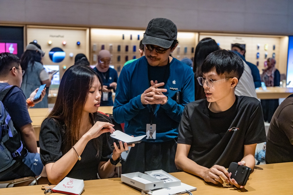 Apple staff assist customers during the first day of sale of the iPhone 16 smartphone at an Apple store at the Tun Razak Exchange (TRX) in Kuala Lumpur September 20, 2024. — Picture by Firdaus Latif