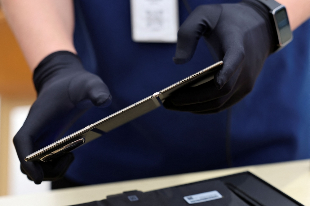 A staff member prepares a Huawei Mate XT for a customer as the tri-foldable smartphone goes on sale at a Huawei flagship store in Beijing September 20, 2024. — Reuters pic  