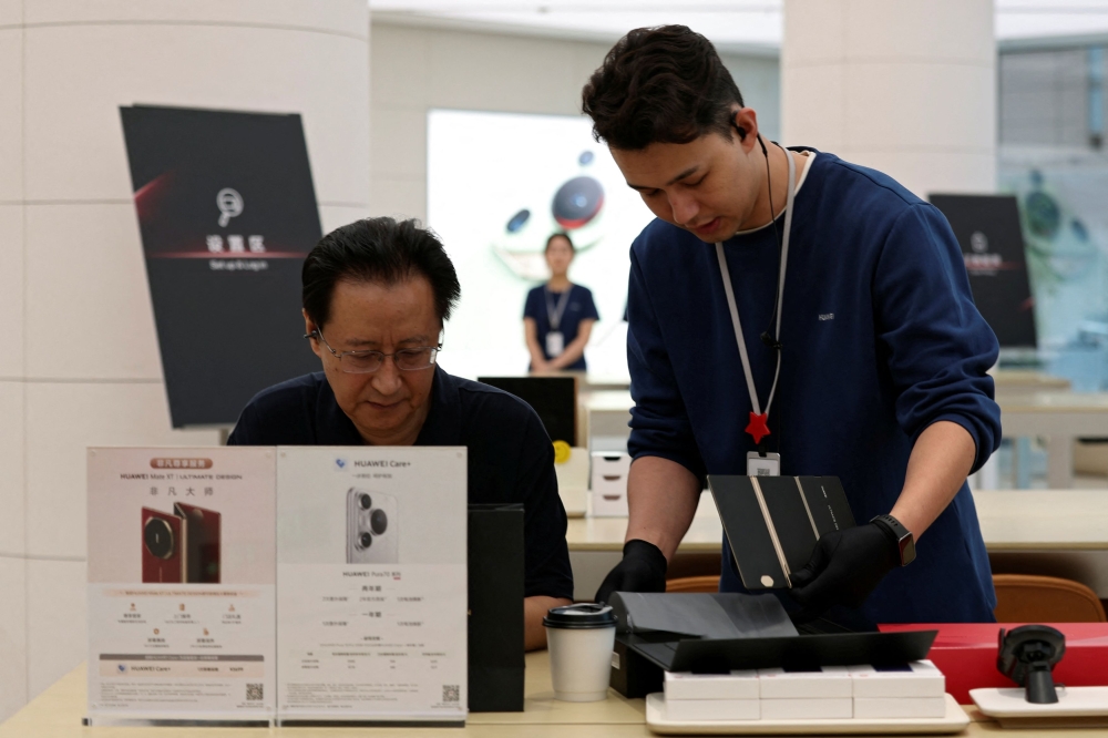 A staff member helps a customer with his Huawei Mate XT as the tri-foldable smartphone goes on sale at a Huawei flagship store in Beijing September 20, 2024. — Reuters pic  