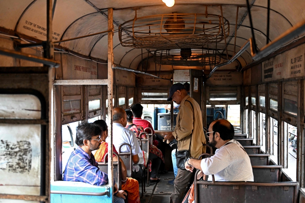 In this photo taken on September 8, 2024, a conductor (2nd right) collects tickets as passengers commute in a tram along a street in Kolkata. — AFP pic