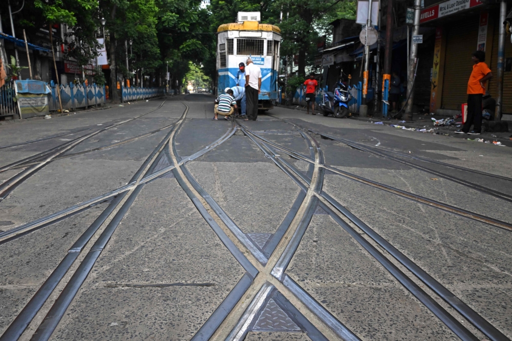 Tram employees manually change the track lane along a street in Kolkata September 18, 2024. — AFP pic