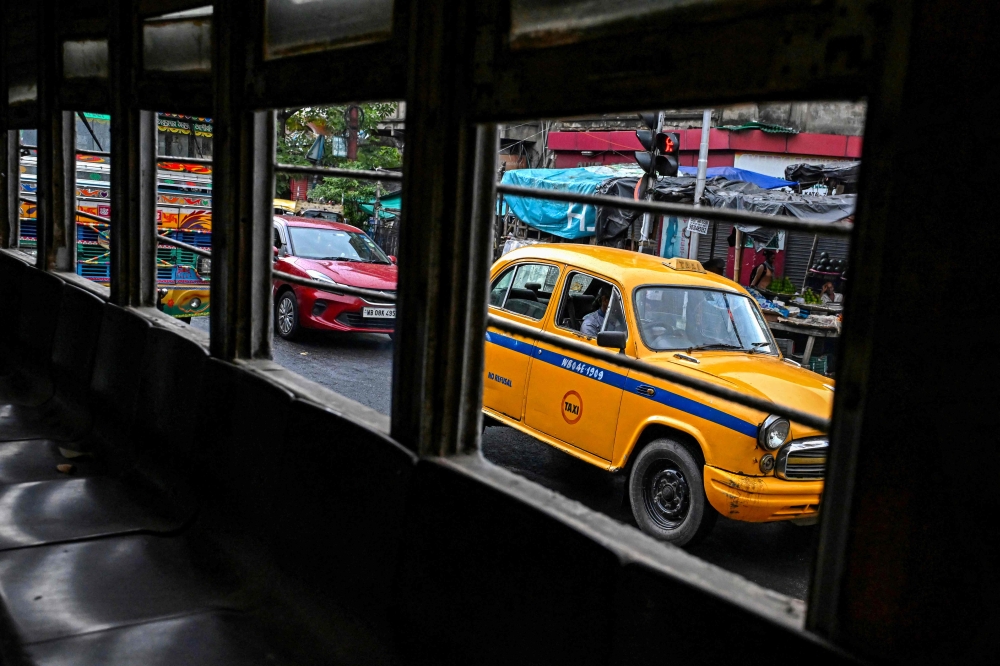 Vehicles drive past an empty tram along a street in Kolkata September 8, 2024. — AFP pic