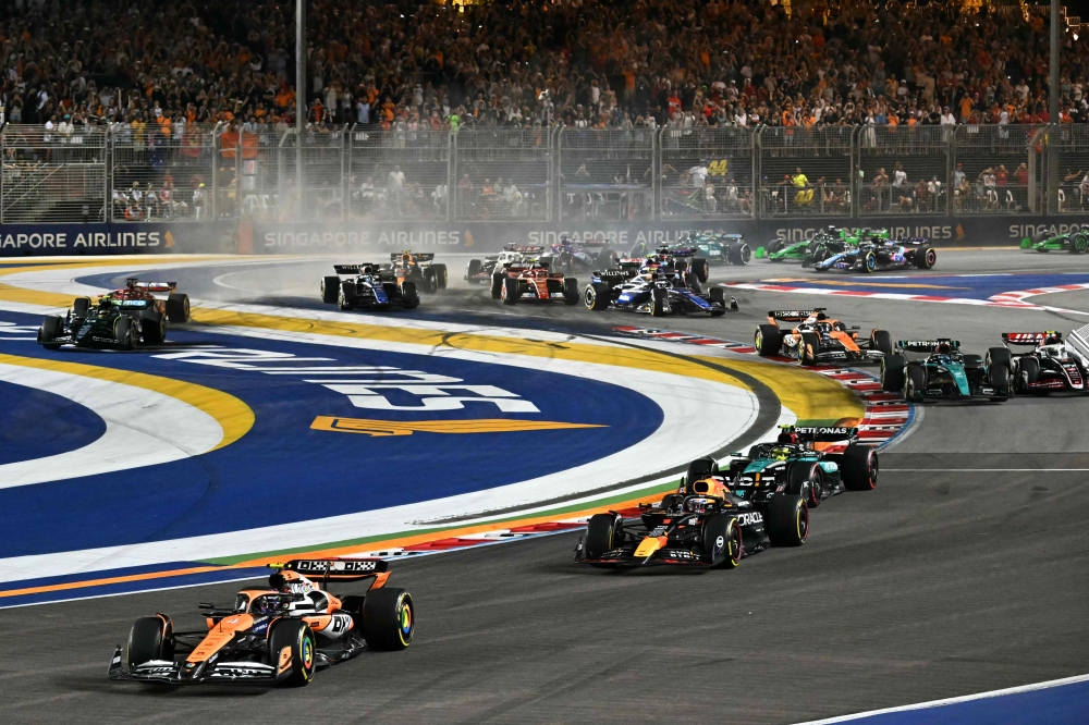 McLaren's British driver Lando Norris (left) leads the pack as he drives at the start of the Formula One Singapore Grand Prix night race at the Marina Bay Street Circuit in Singapore September 22, 2024. — AFP pic