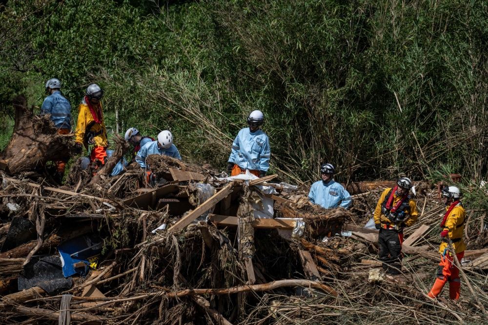 Rescue personnel search for missing people in debris washed away from flooding along the Tsukada river following heavy rain in Wajima city, Ishikawa prefecture on September 23, 2024. — AFP pic