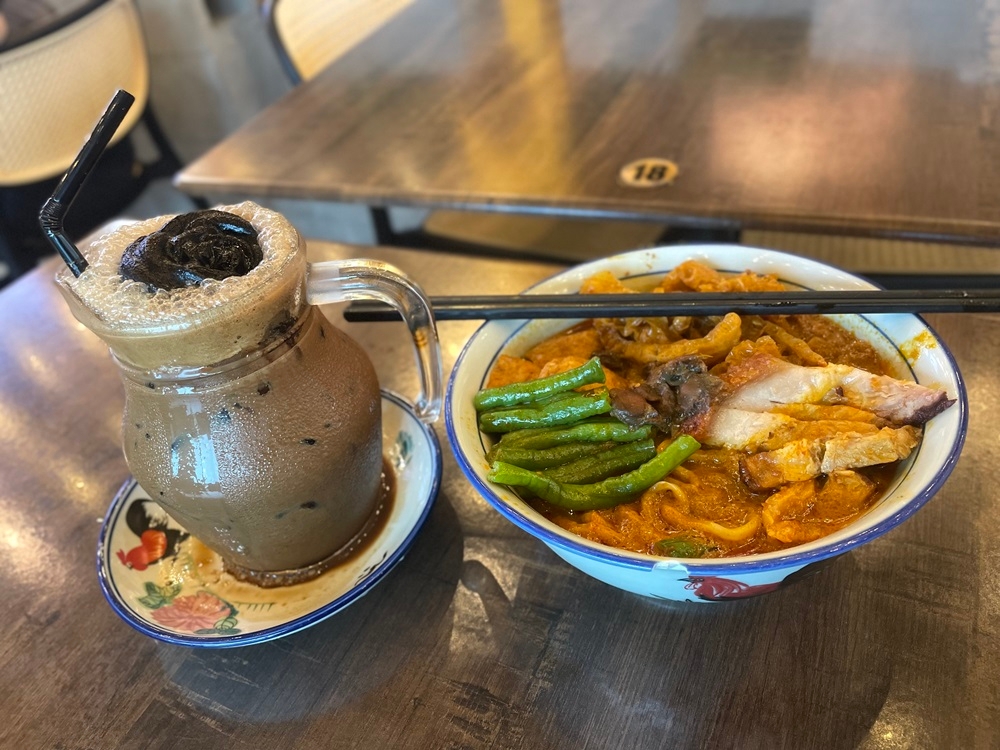 The iced white coffee at Golden Alley Kopi comes with rose shaped frozen coffee extract and their signature curry noodles is a must try. — Picture by John Bunyan