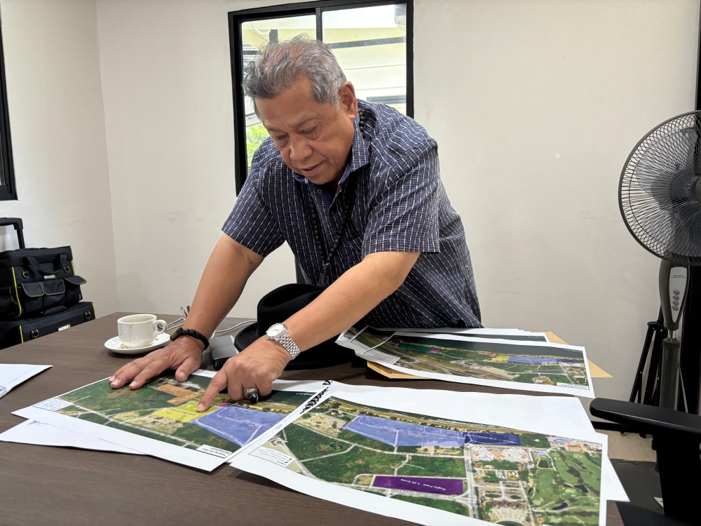 Pandikar showing the map of Tanjung Aru beach and the proposed plans for its redevelopment which includes improved traffic planning — Picture by Julia Chan