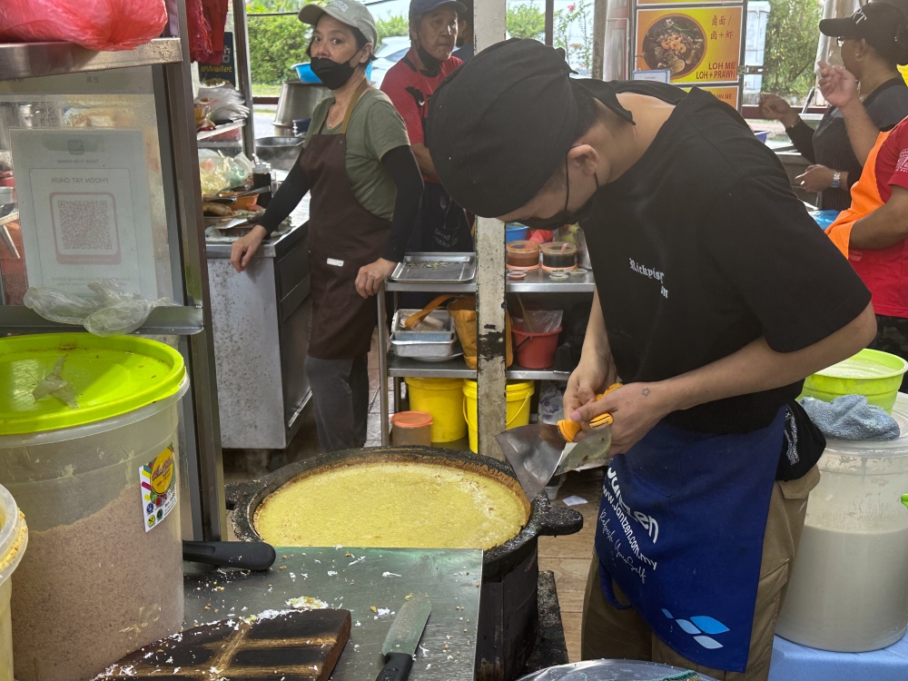 The batter is poured into the large pan and covered with a lid to cook until the edges crisp up.  — Picture by Lee Khang Yi