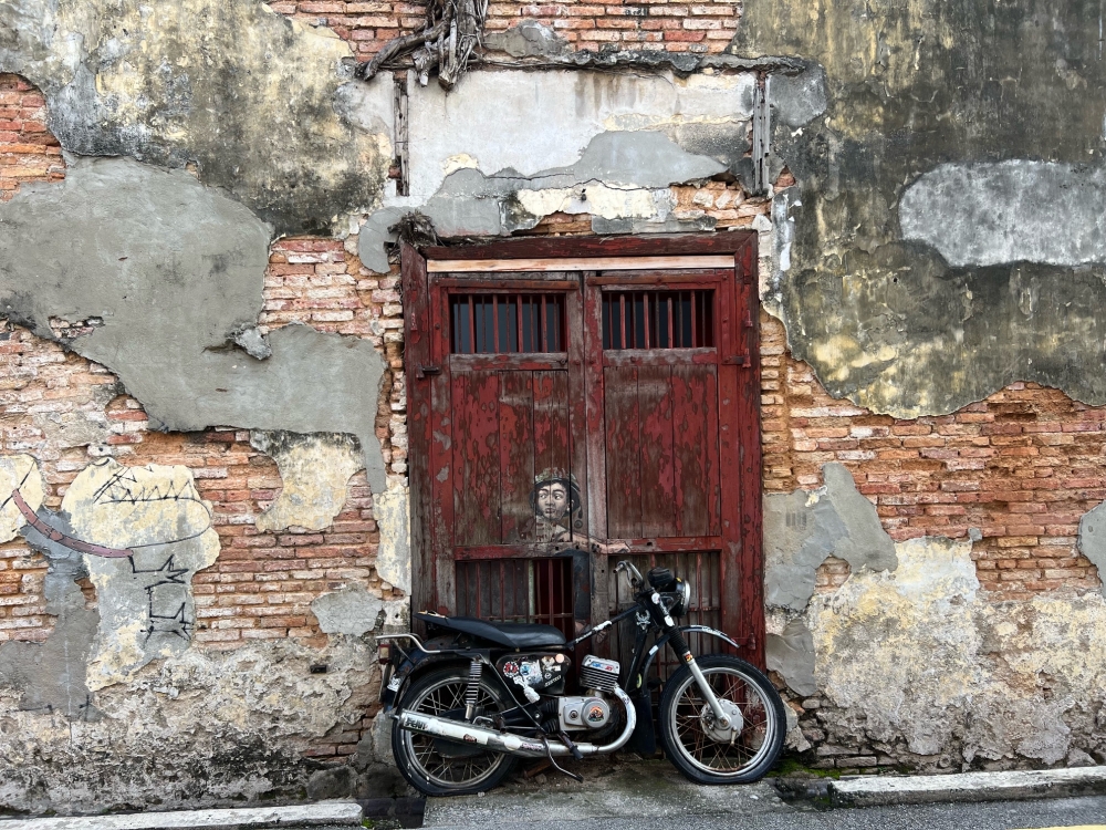 The 'Boy on Motorcycle' street art at Ah Quee Street has already started its restoration progress.  — Picture by Opalyn Mok