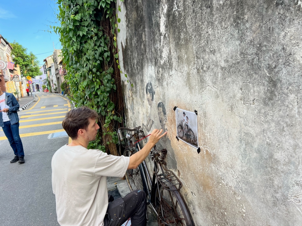 Ernest Zacharevic had previously restored the murals back in 2016 and again in 2019 when the 'Children on Bicycle' was vandalised. — Picture by Opalyn Mok