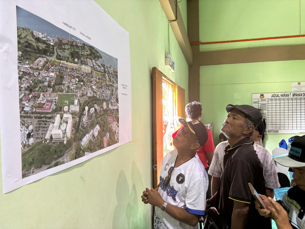 Villagers of Kampung Sembulan Tengah scrutinise the map of earmarked land. — Picture by Julia Chan