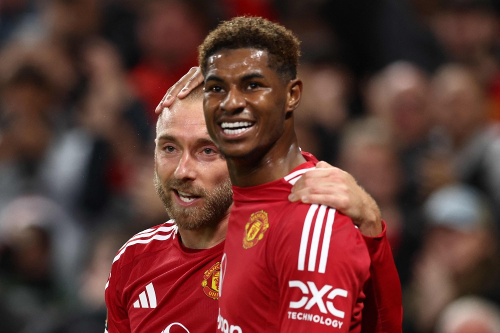 Manchester United's midfielder Christian Eriksen (left) celebrates with Marcus Rashford after scoring his teams first goal during the Uefa Europa league stage football match between Manchester United and FC Twente at Old Trafford stadium in Manchester, north west England, on September 25, 2024.