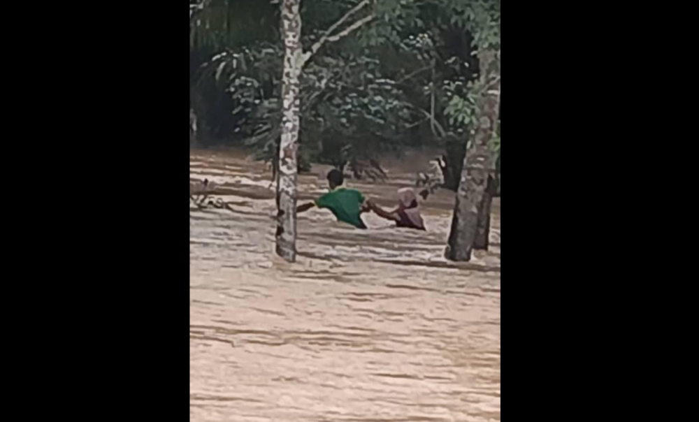 A photo believed to be of Salmah Mat Zain, 46, and her disabled son, Muhammad Rosman Rohaidi, 19, wading through flood waters Kampung Tanjung Kiri sent by a member of the public in an emergency call to the authorities before they went missing on September 28, 2024. — Picture from Facebook/Bomba Kuala Nerang