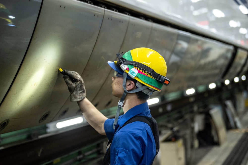 A staff member checks a train at the JR Central Oi Shinkansen depot in the Shinagawa district of Tokyo July 24, 2024. — AFP pic