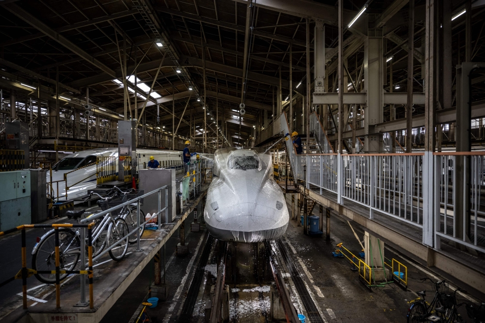 Staff members clean the front of a train at the JR Central Shinkansen depot in the Shinagawa district of Tokyo July 24, 2024. — AFP pic