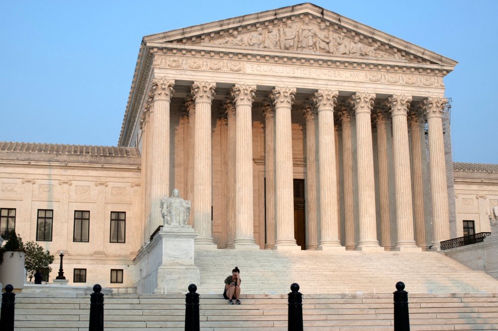 A woman sits on the steps of the US Supreme Court in Washington August 14, 2024. In 2022, the conservative-dominated Supreme Court of the United States overturned the landmark 1973 ‘Roe v Wade’ decision that had enshrined a woman’s right to a termination for half a century. — Reuters pic  