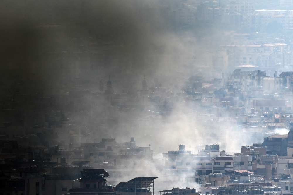 Smoke rises over Beirut's southern suburbs during Israeli strikes on September 28, 2024. — AFP pic