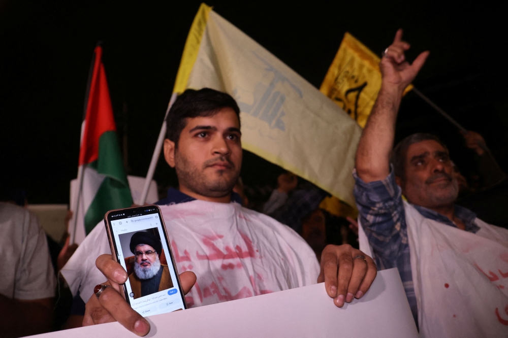 A protester shows a picture of Hezbollah leader Sayyed Hassan Nasrallah on his mobile phone during an anti-Israel protest following an Israeli strike on Lebanon, in Tehran, Iran, September 28, 2024. — Majid Asgaripour/Wana (West Asia News Agency) pic via Reuters 