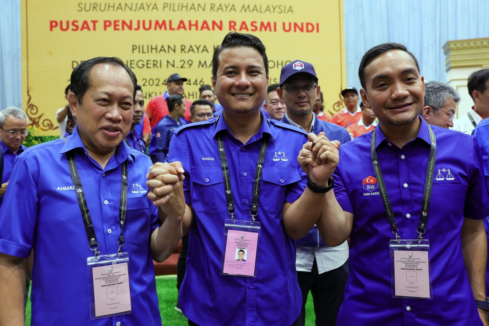 Johor Menteri Besar Datuk Onn Hafiz Ghazi (right) with BN candidate Syed Hussien Syed Abdullah (centre) and Deputy Works Minister Datuk Seri Ahmad Maslan (left) celebrate after the announcement of the win in the Mahkota State Legislative Assembly by-election at Dewan Tunku Ibrahim Ismail September 28, 2024. — Bernama picSuburban 