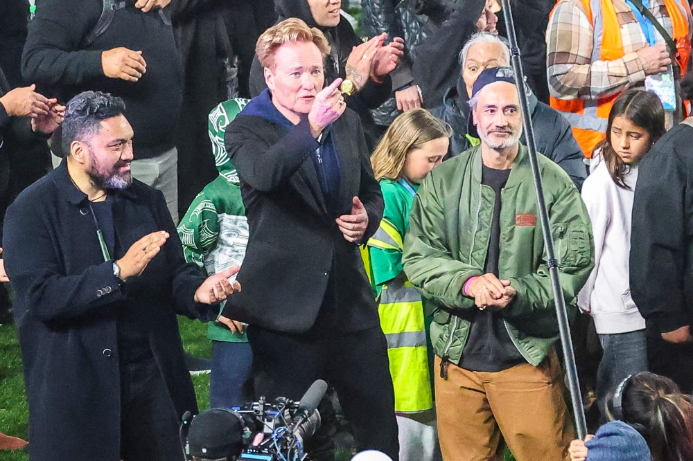 New Zealand filmmaker-actor Taika Waititi (2nd right) and US comedian and television personality Conan O'Brien (2nd left) gesture as people gather in a world record attempt for the largest mass Haka at Eden Park in Auckland on September 29, 2024.