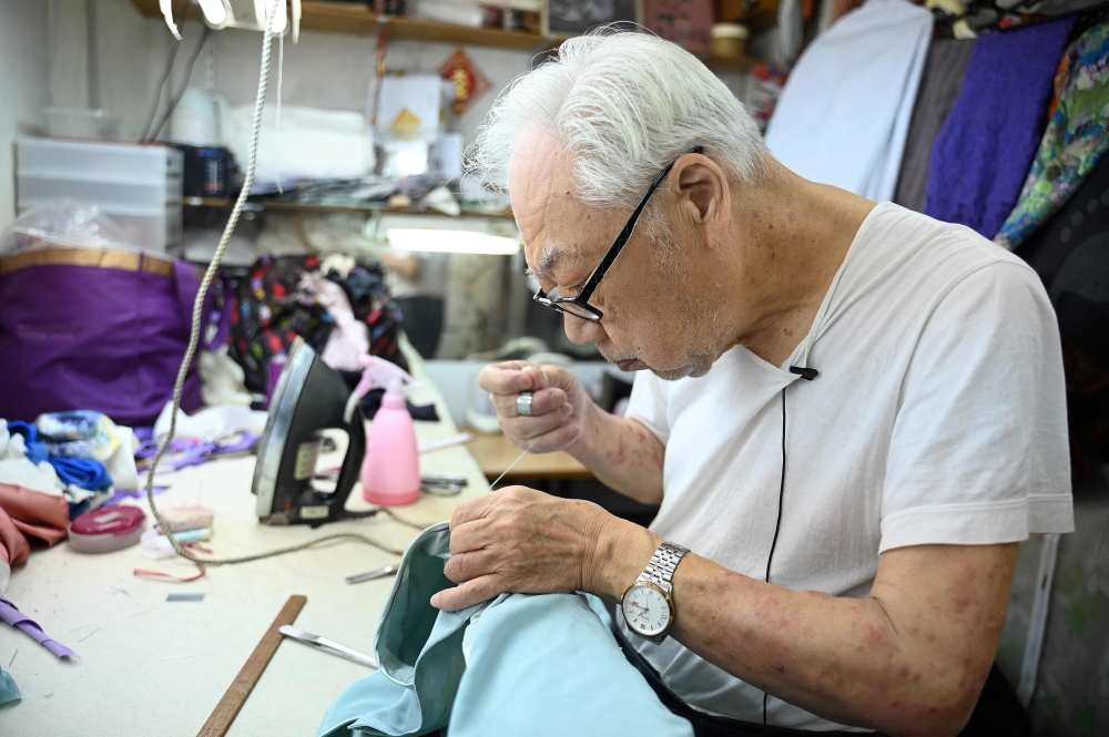 Bent over a magenta chiffon fabric, the elderly Hong Kong tailor wearing thick glasses meticulously stitches on embroidered butterflies, working to transform the shimmering material into a cheongsam. — AFP pic