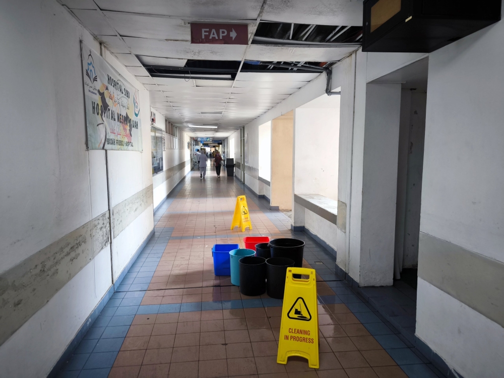 Pails placed on the floor to collect water in the walkway between the maternity ward and operating theatre in the Sibu Hospital. — The Borneo Post pic