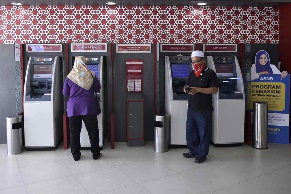 Customers use automated teller machines at a Bank Islam branch in Shah Alam on March 26, 2020. —  Picture by Miera Zulyana