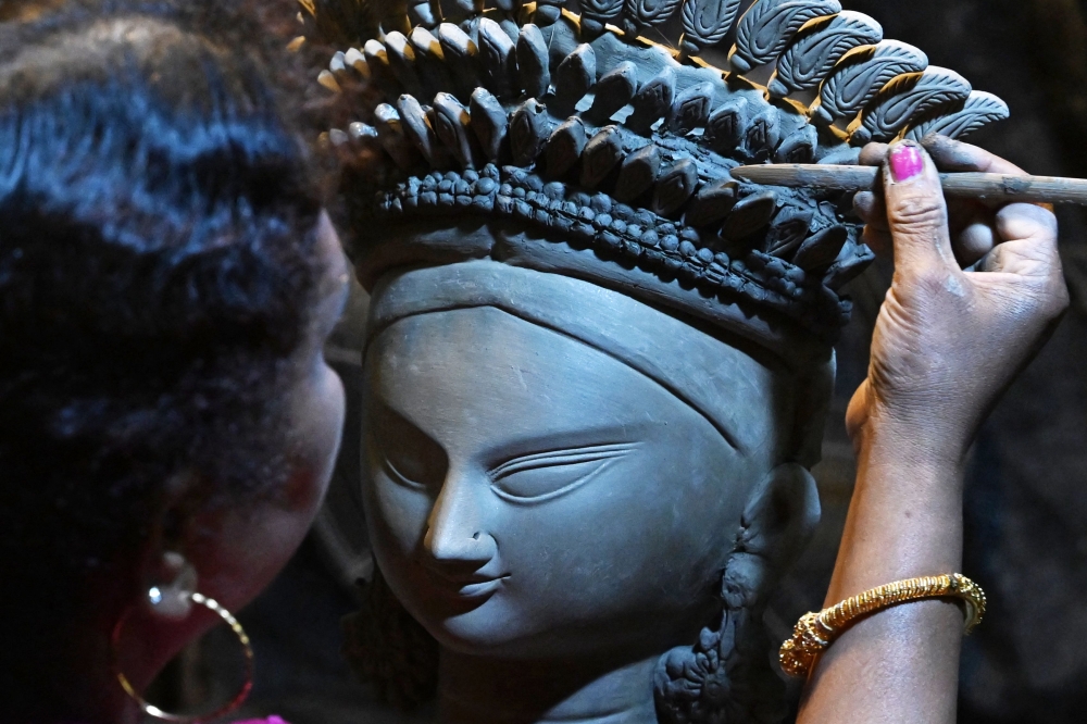 An artisan works on a clay idol of Hindu goddess Durga, ahead of the Durga Puja festival at Kumartoli in Kolkata. — AFP pic