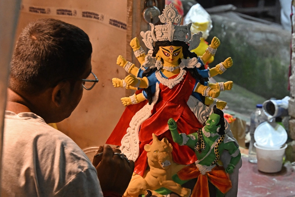 An artisan works on a clay idol of Hindu goddess Durga. — AFP pic