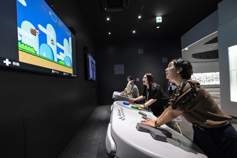 This photo taken on September 24, 2024 shows visitors interacting with an early ‘Super Mario’ game and other games during a media preview of the new Nintendo Museum, located inside a renovated old factory, in suburbs of Kyoto. — AFP pic