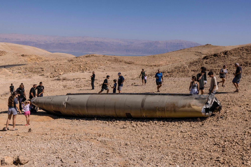 People visit the site of the remains of an Iranian missile in the Negev desert near Arad on October 3, 2024, in the aftermath of an Iranian missile attack on Israel. Israel vowed to make Iran ‘pay’ for firing a barrage of missiles at its territory, with Tehran warning on October 2 it would launch an even bigger attack it is targeted. — AFP pic