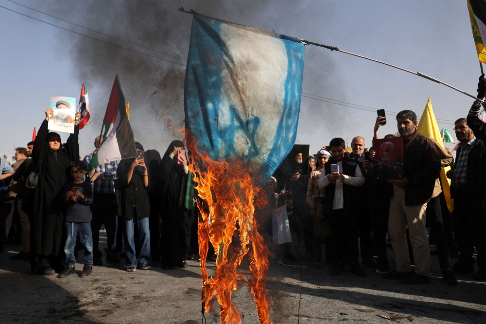 Iranians burn a painted Israeli flag during a gathering to support the IRGC attack on Israel, in Tehran October 2, 2024. — Majid Asgaripour/Waba (West Asia News Agency) pic via Reuters 