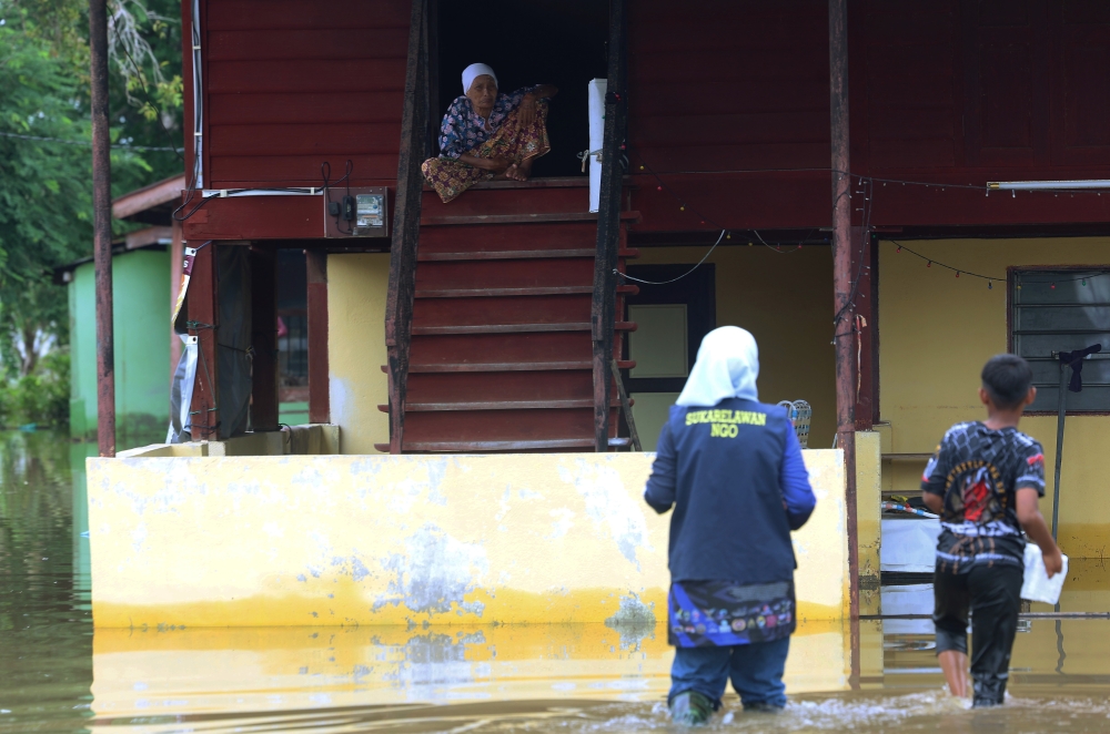 A file photograph shows an aid worker approaching a senior citizen who refused to evacuate during the floods at Kampung Alor Melintang, near Sungai Baru in Alor Setar, Kedah on September 22, 2024. — Bernama pic