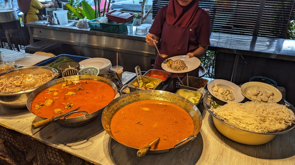 ‘Nasi dagang’ being plated up in front of a massive wok of ‘gulai ikan tongkol’. — Picture by Ethan Lau