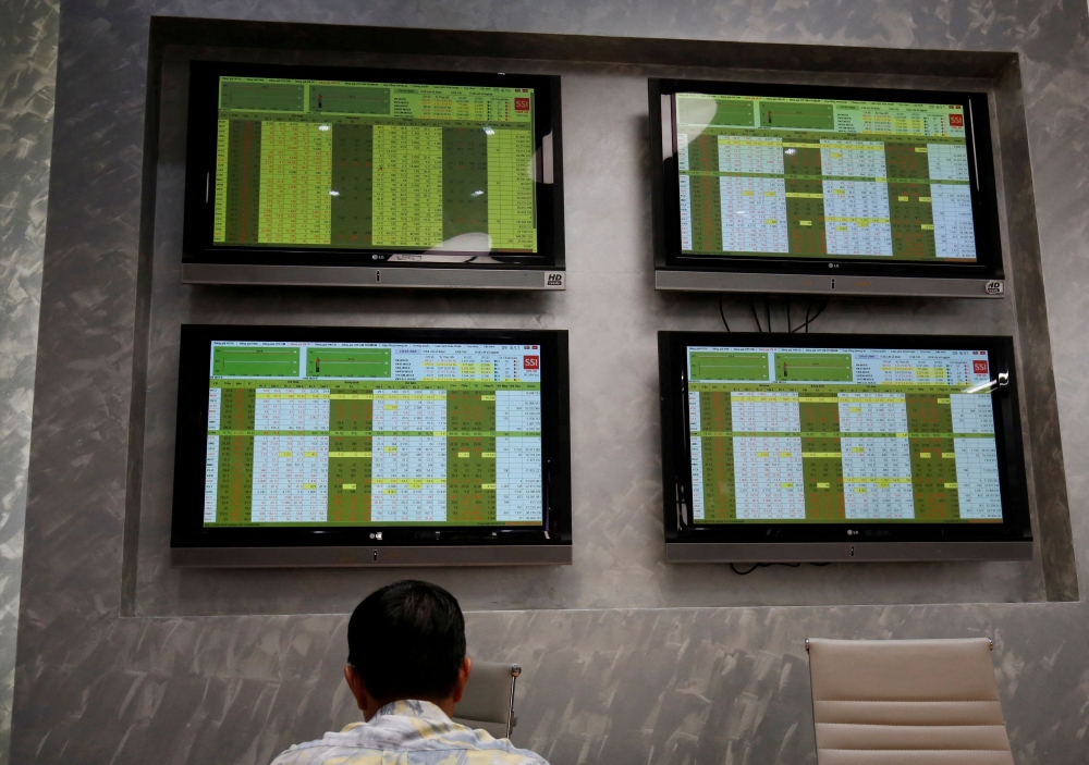 An investor sits in front of screens showing stock board information at a securities company in Hanoi July 6, 2018. — Reuters pic  