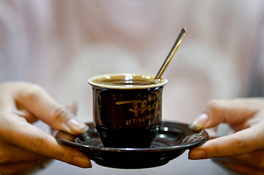 This photo taken on August 21, 2024 shows an employee serving coffee to a customer at a cafe in Hanoi. — AFP pic