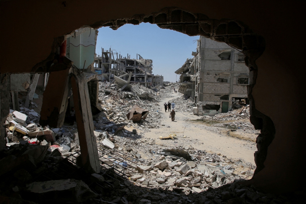 Palestinians walk past the rubble of houses destroyed during the Israeli military offensive, amid Israel-Hamas conflict, in Khan Younis in the southern Gaza Strip July 10, 2024. — Reuters pic