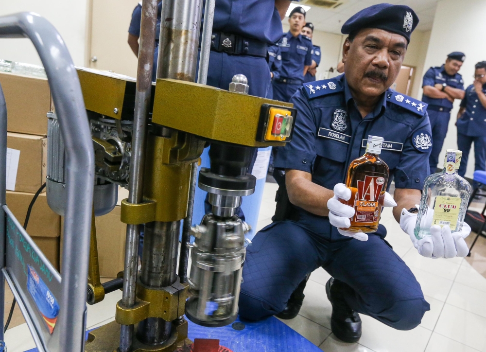 State Customs Department director Datuk Roselan Ramli shows the fake liquor seized in Kampung Valdor, Sungai Jawi. — Picture by Opalyn Mok