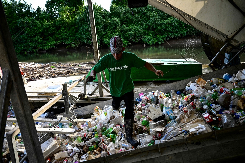 An employee of the NGO ‘Marea Verde’ walks over a conveyor belt of the gigantic hydraulic and solar-powered machine called ‘Wanda’ that collects garbage from the Juan Diaz River in Panama City on October 1, 2024. — AFP pic