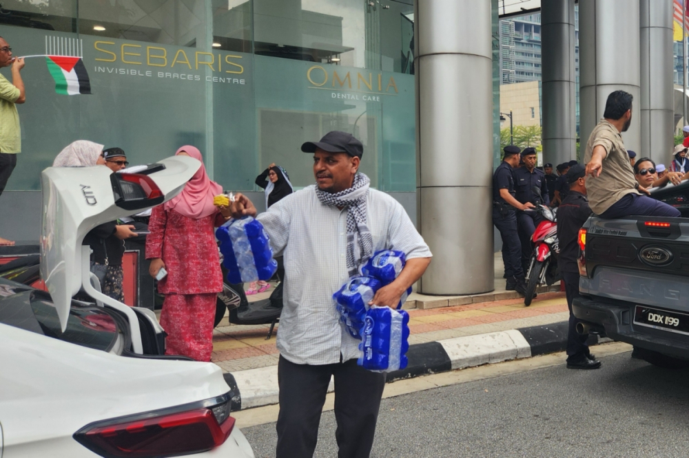 Waled Al Fateh from Yemen distributing water to participants of the rally. — Picture by Arif Zikri