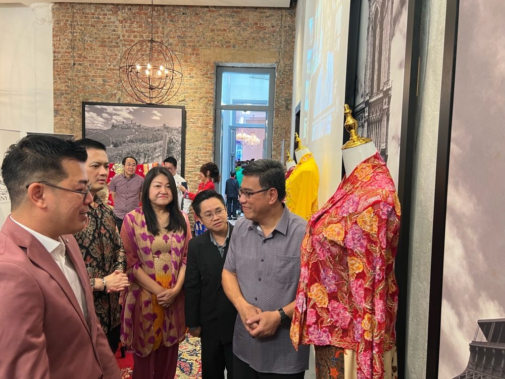 Kenny Loh (far left) explaining his nyonya kebaya designs to Penang executive councillor Wong Hon Wai (in grey shirt). — Picture by Opalyn Mok