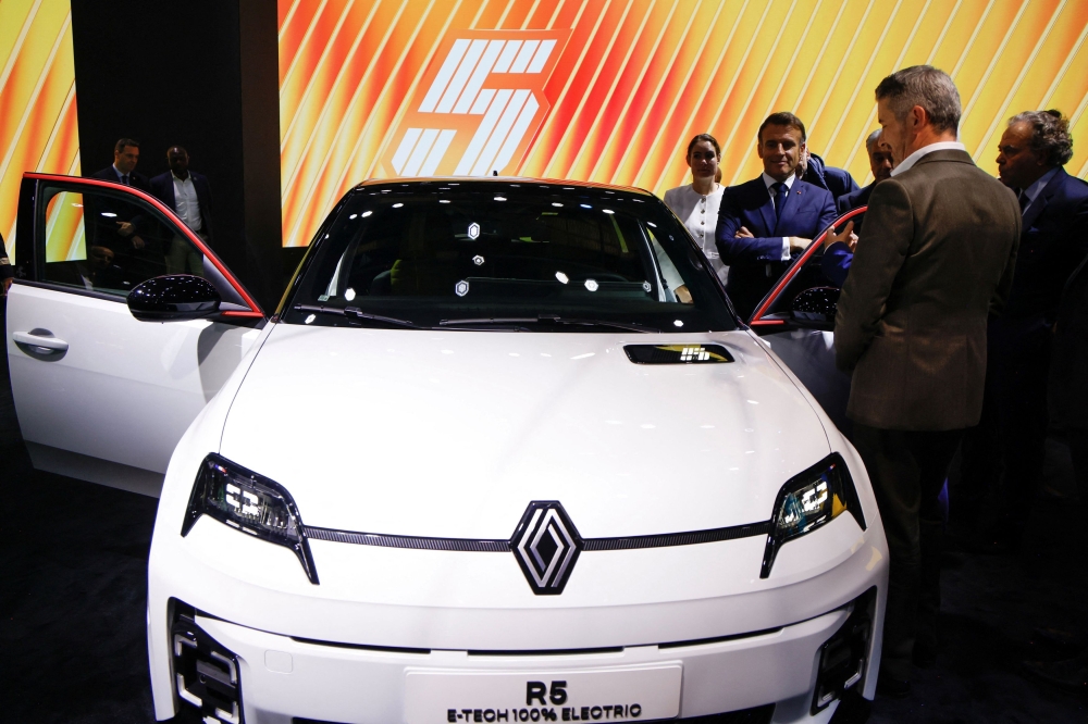 French President Emmanuel Macron stands by a new electric Renault R5 E-Tech as he visits the Paris Motor Show at Paris Expo Porte de Versailles in Paris October 14, 2024. — Ludovic Marin/Pool pic via Reuters  