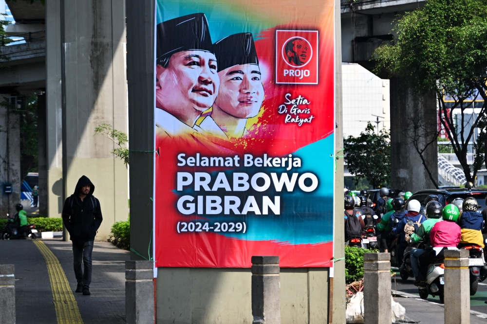 A pedestrian walks near a banner congratulating Indonesia's president-elect Prabowo Subianto and vice president-elect Gibran Rakabuming Raka ahead of their October 20 inauguration, in Jakarta on October 17, 2024. — AFP pic