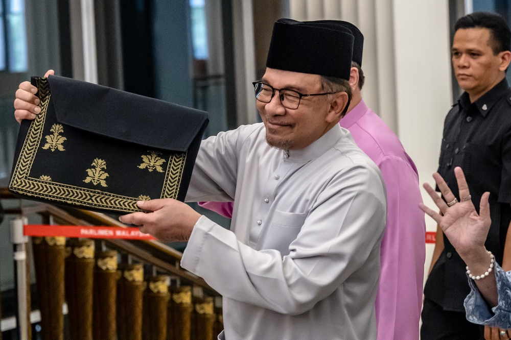 Prime Minister Datuk Seri Anwar Ibrahim displays a briefcase with a songket motif as he arrives in Parliament to table Budget 2025, in Kuala Lumpur on October 18, 2024. — Picture by Firdaus Latif