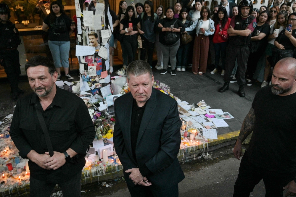 The senior Payne passing the tributes left by mourning fans. — AFP