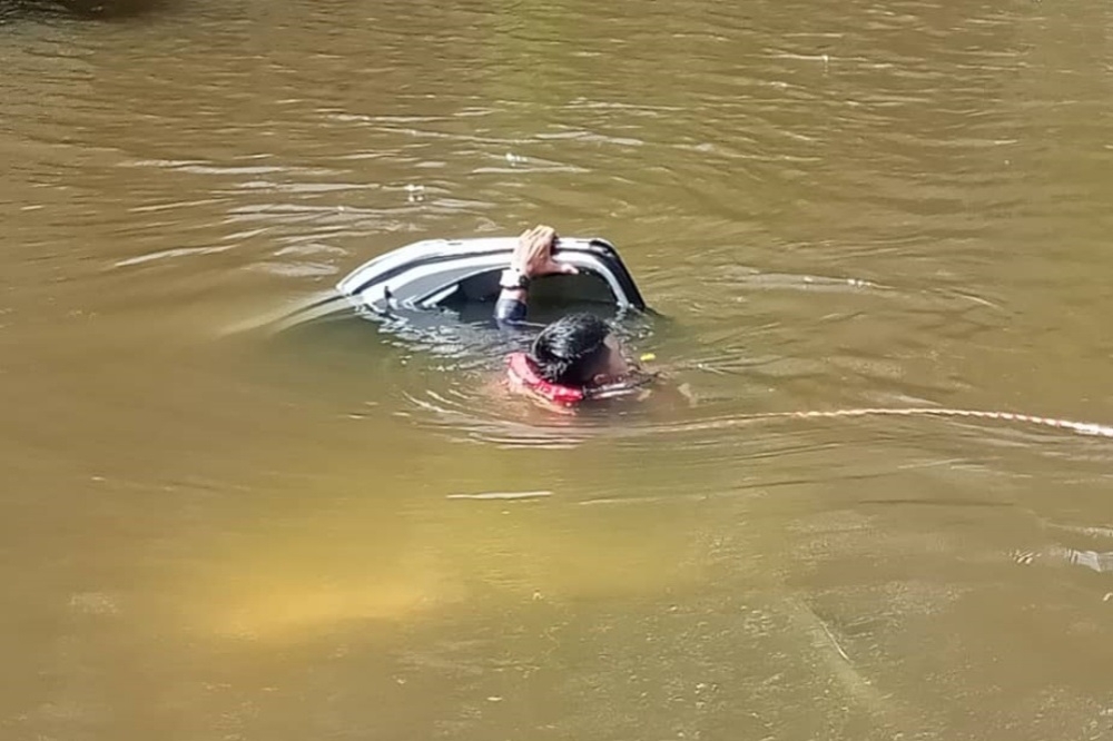 A rescue personnel extricating victims still trapped in the submerged vehicle. — Picture courtesy of the Fire and Rescue Department 