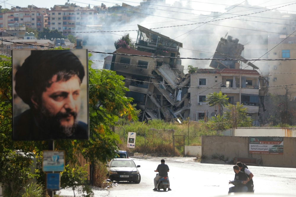 People drive next to a building, targeted in an Israeli airstrike the night before, in Beirut’s southern suburbs on October 20, 2024, amid the ongoing war between Hezbollah and Israel. — AFP pic 