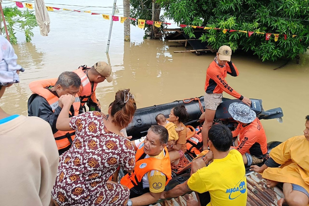 This handout photo taken and released on October 23, 2024 by the Philippine Coast Guard (PCG) shows residents affected by Tropical Storm Trami being evacuated from the roofs of their submerged houses, in Libon town, Albay province, South of Manila. — AFP pic