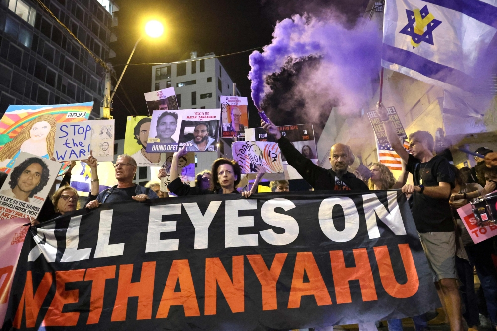 Relatives and supporters of Israelis held hostage in Gaza since the October 7 attacks by Palestinian militants, lift placards and national flags calling on the US to intervene for their release, during a demonstration in the Israeli coastal city of Tel Aviv as the US Secretary of State visits on October 22, 2024, — AFP pic