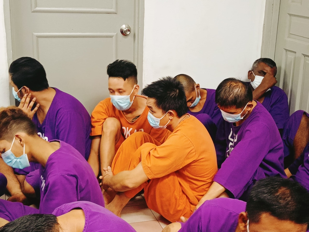 Two of the Vietnamese suspects (centre in orange attire) at the Johor Baru Magistrate’s Court today. — Picture by Ben Tan